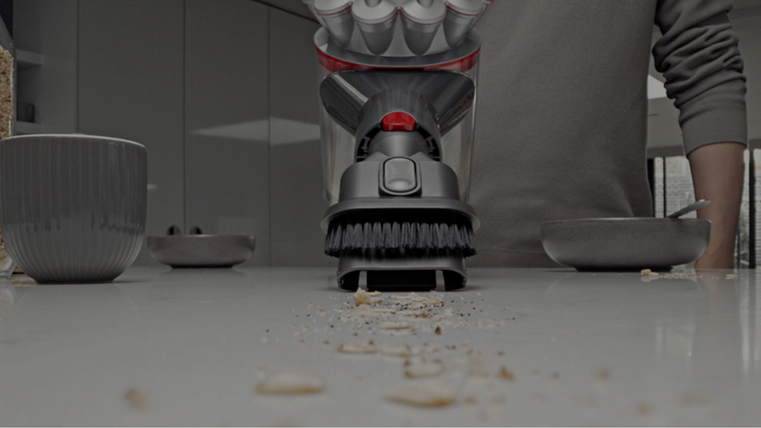 A Dyson Car+Boat handheld vacuum is used to clean a kitchen.